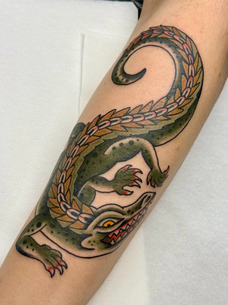 Traditional alligator tattoo wrapping around the forearm