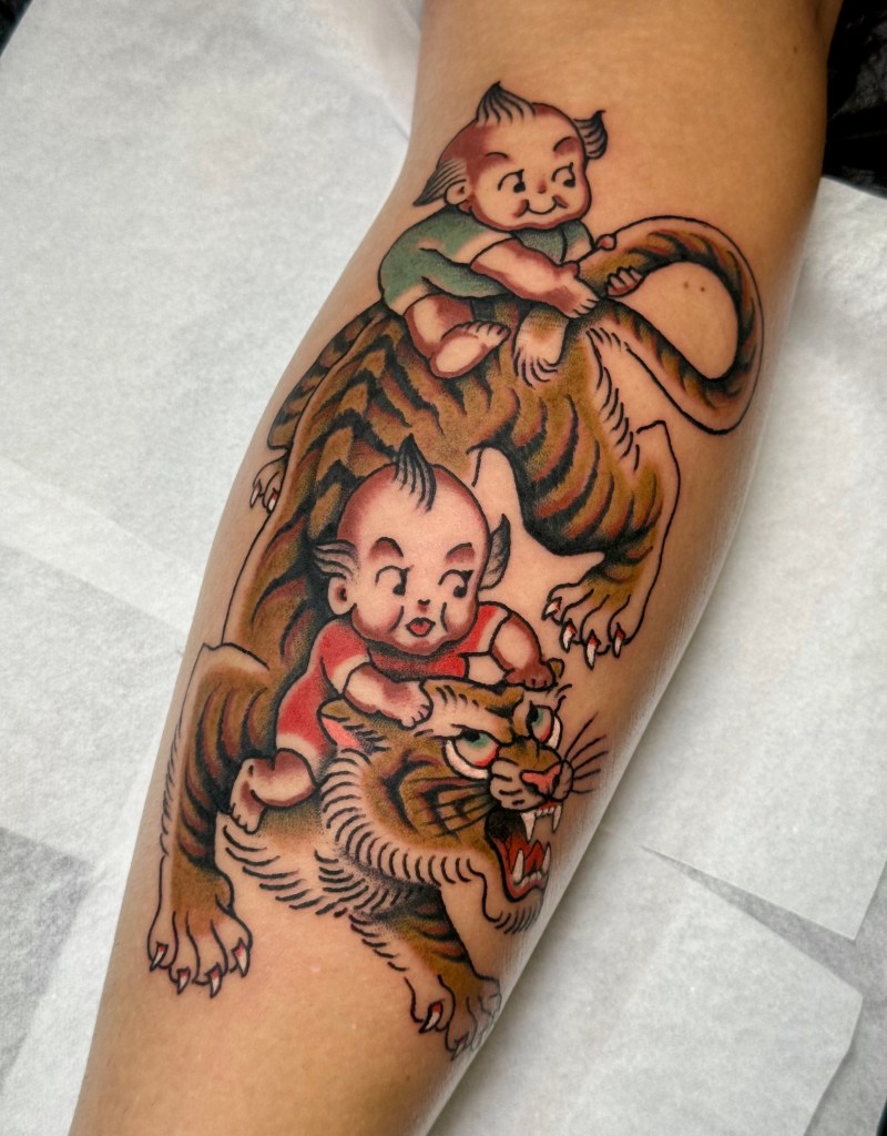 Traditional tiger with two kewpie dolls tattooed on the shin