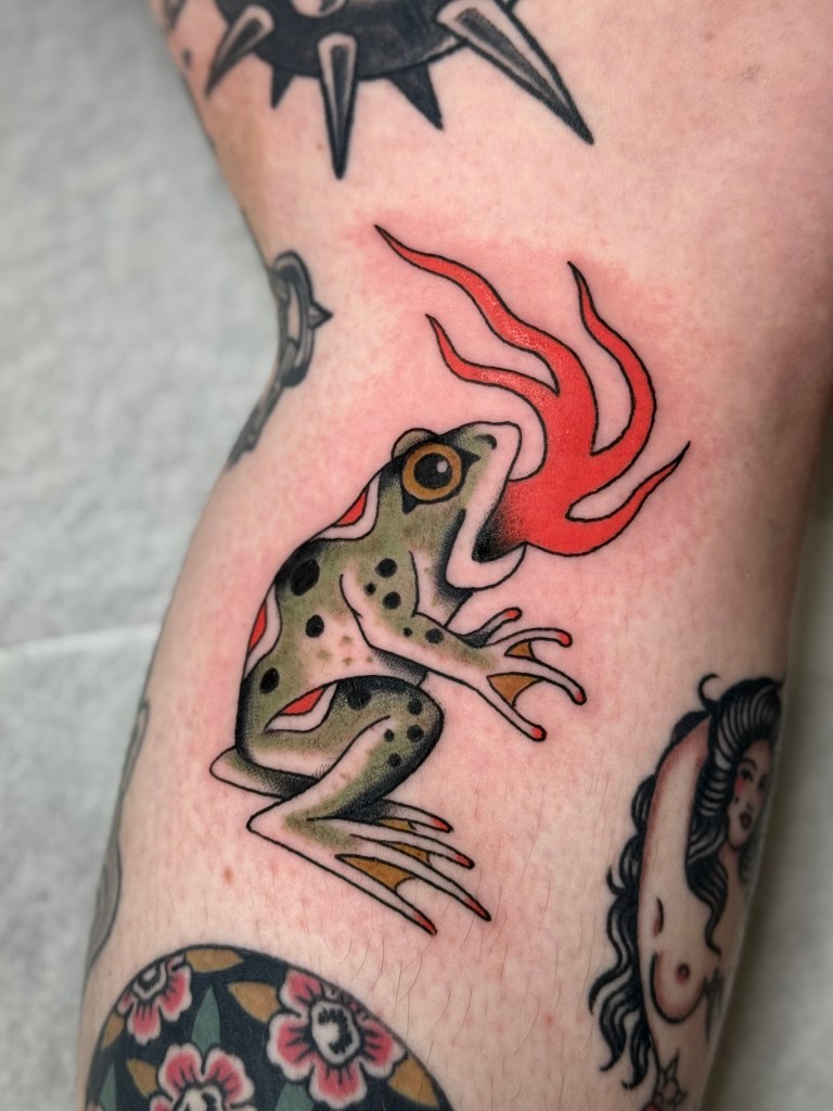Traditional flaming frog tattoo in a patchwork sleeve