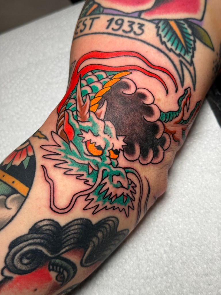 Traditional Japanese dragon head tattoo on the elbow